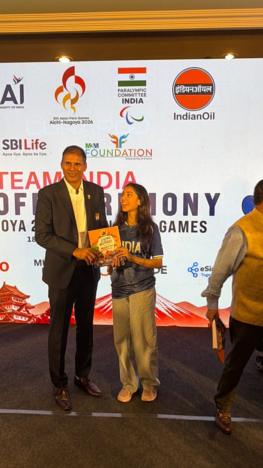 Sharanya Kheruka and Dr Devendra Jhajharia holding Living Histories on stage